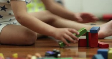 Toddler playing with toys in bedroom at night wearing pajamas contructing with wooden puzzle pieces