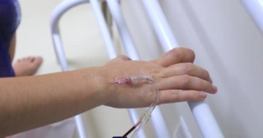 hand connected to IV drip at hospital holding on bar