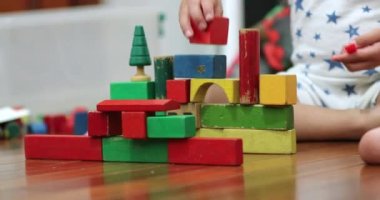 Toddler boy playing with toys in room wooden buildings blocks