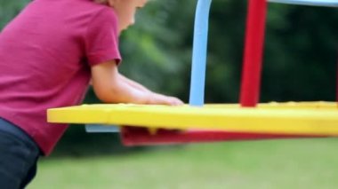 Child spinning around with carousel outside in park