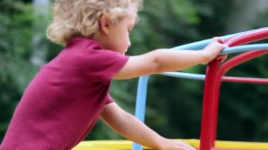Child boy spinning around carousel at playground outside