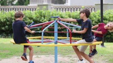 Children at playground with carousel spinning round playing with toy gun