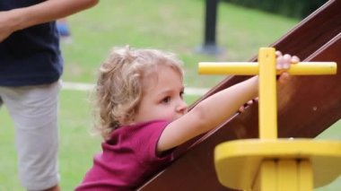Little boy toddler playing in playground climbing slider