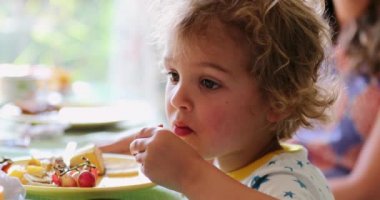 Toddler baby boy eating toast marmelade in morning breakfast table
