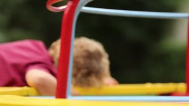 Cute toddler boy spinning in playground carousel park