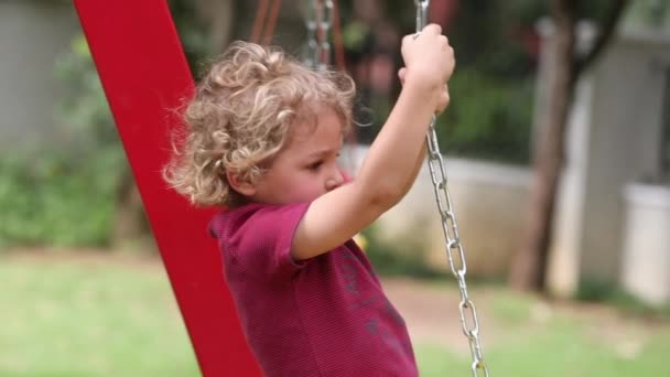 Little toddler boy holding into playground structure