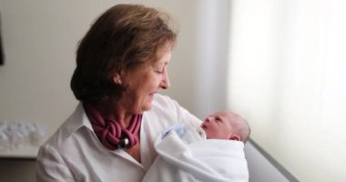 Newborn baby infant being held by grand-mother, real life and authentic