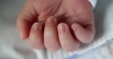 Newborn baby infant asleep, close-up of tiny little hand in macro detail