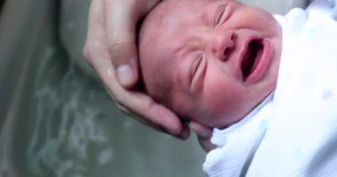 Bathing newborn baby, washing infant face with soap