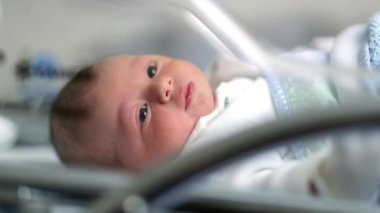 Newborn baby inside hospital crib during first day of life