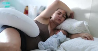 Candid mother sleeping with newborn baby in morning