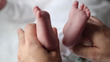 Newborn baby feet mother holding infant foot showing to camera