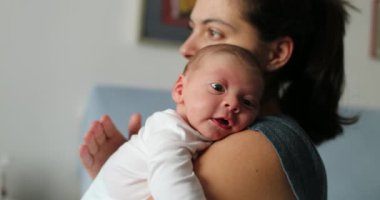 Mother tapping newborn baby back to help with hiccups