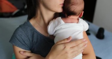 Mother tapping newborn baby back to help with hiccups