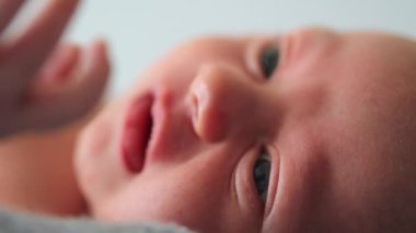 Closeup of newborn baby infant looking and observing macro face and eyes