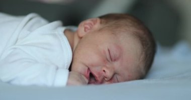 Newborn baby infant laying in bed being adorable and cute