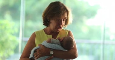 Grand-mother calming and holding newborn baby in arms