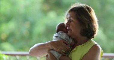 Grand-mother holding newborn baby infant grand-son