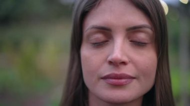 Young woman closing eyes in meditation. Contemplative girl opening eyes to camera smiling. Happy meditative person