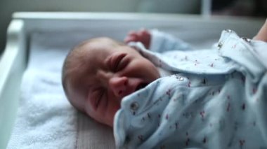 Cute tiny newborn baby observing camera