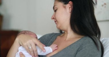 Mother holding newborn baby during first month of life casual and candid real life