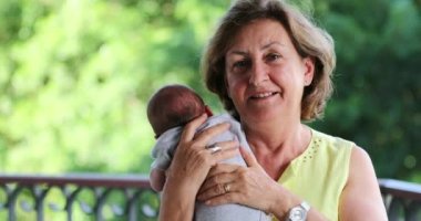 Grandma holding newborn baby grandson