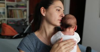 Mother tapping newborn baby back to help with hiccups