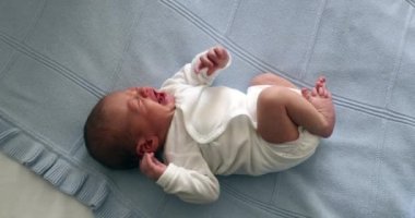 Newborn baby infant crying in bed