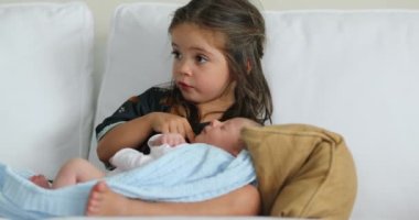 Beautiful cute family moment sister kissing newborn baby brother