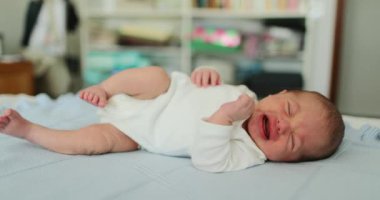 Newborn baby in bed awake stretching waking up