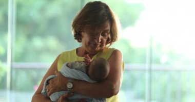 Happy grand-mother holding newborn baby infant in arms feeling joy