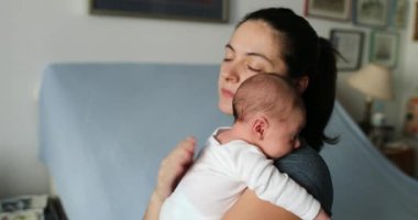Mother tapping newborn baby back to help with hiccups