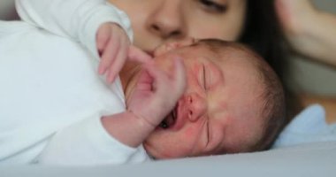 Newborn baby infant crying laying in bed during first week of life