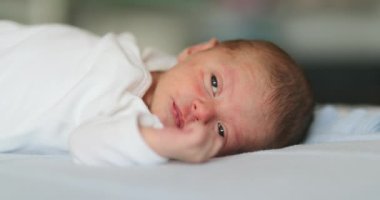 newborn baby infant face waking up and opening eyes