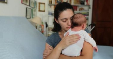 Mom tapping newborn baby in the back helping with hiccups