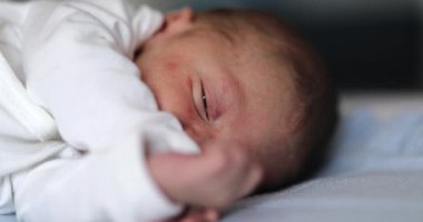 Newborn baby falling asleep closing eyes. Close-up of infant face closing eye sleeping