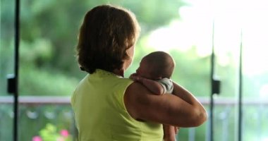 Back of grand-mother holding newborn baby infant in arms candid