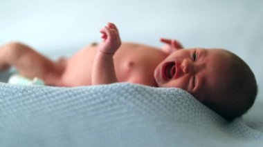 Newborn baby infant first week of life laid in bed awake