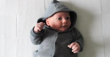 Adorable cute baby infant wearing hoodie clothing layed in bed