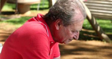 Older man looking at tech cellphone device screen outdoors