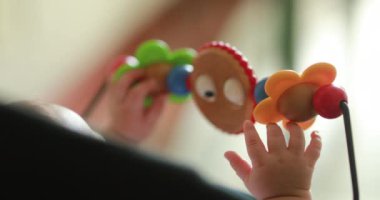 Baby hands playing with toy inside chair crib