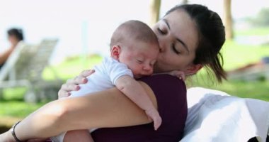 Mother holding newborn baby infant outdoors