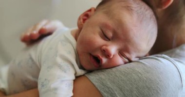 Mother holding newborn baby tapping in the back