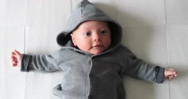 Cute Baby infant laying in bed wearing hoodie