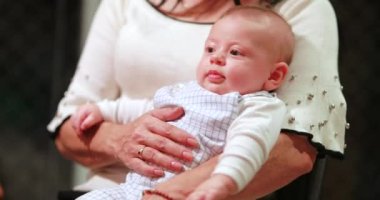Grand-mother holding newborn baby infant in casual candid family moment