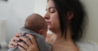 Candid mother holding newborn baby in bed showing love care and affection
