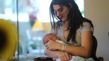 Candid mother holding newborn baby infant at home
