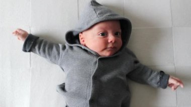 Cute Newborn baby laying in bed wearing hoodie