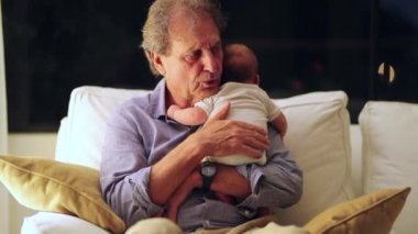 Grandfather holding newborn baby grandson candid grandparents real life authentic moment