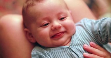 Anne kucağında mutlu bir bebek, gülümsüyor.